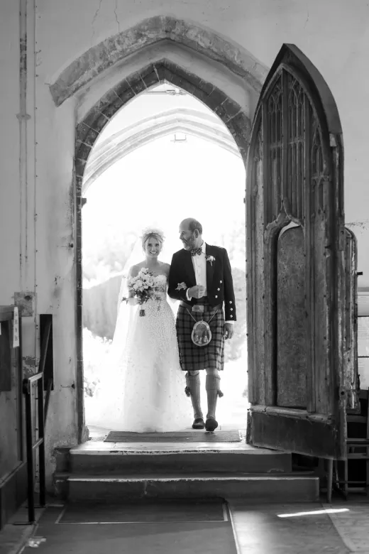 A black and white photo of a bride and groom entering a church.