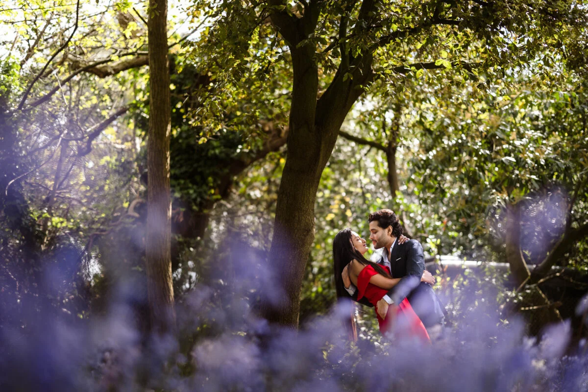 A couple kisses in a field of bluebells.