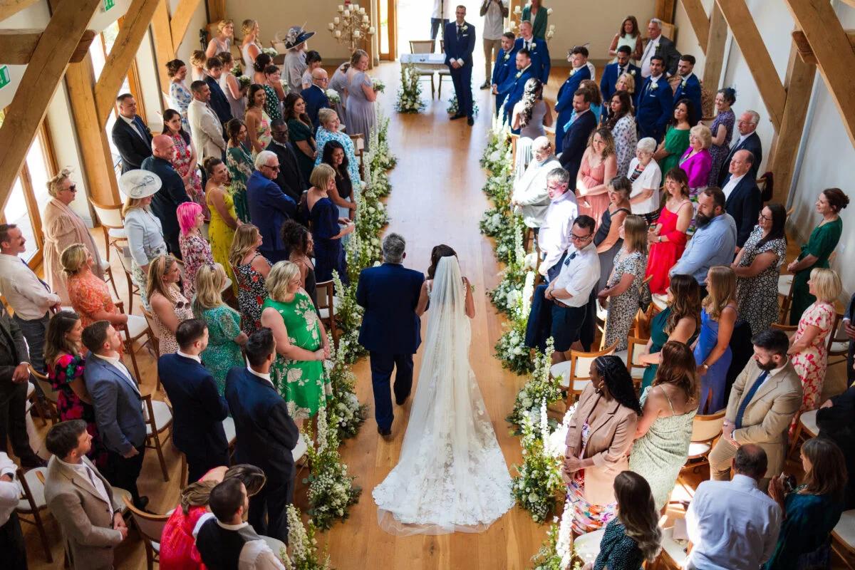 A wedding ceremony in a barn with a bride and groom walking down the aisle.