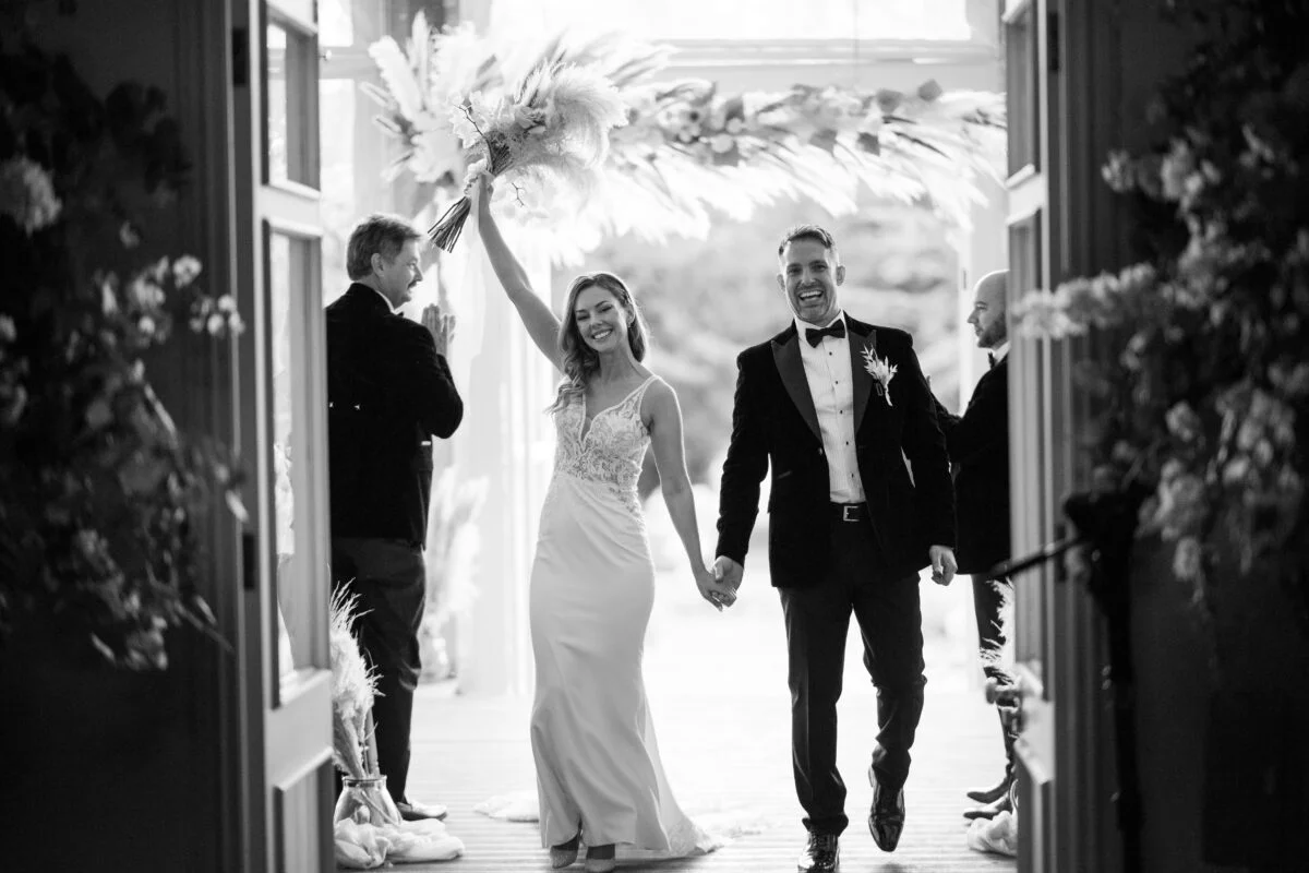 A bride and groom walking out of a doorway.