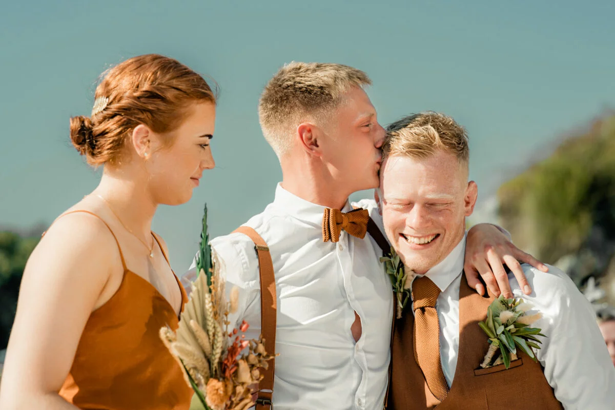 A bride and groom are kissing each other at a beach wedding.