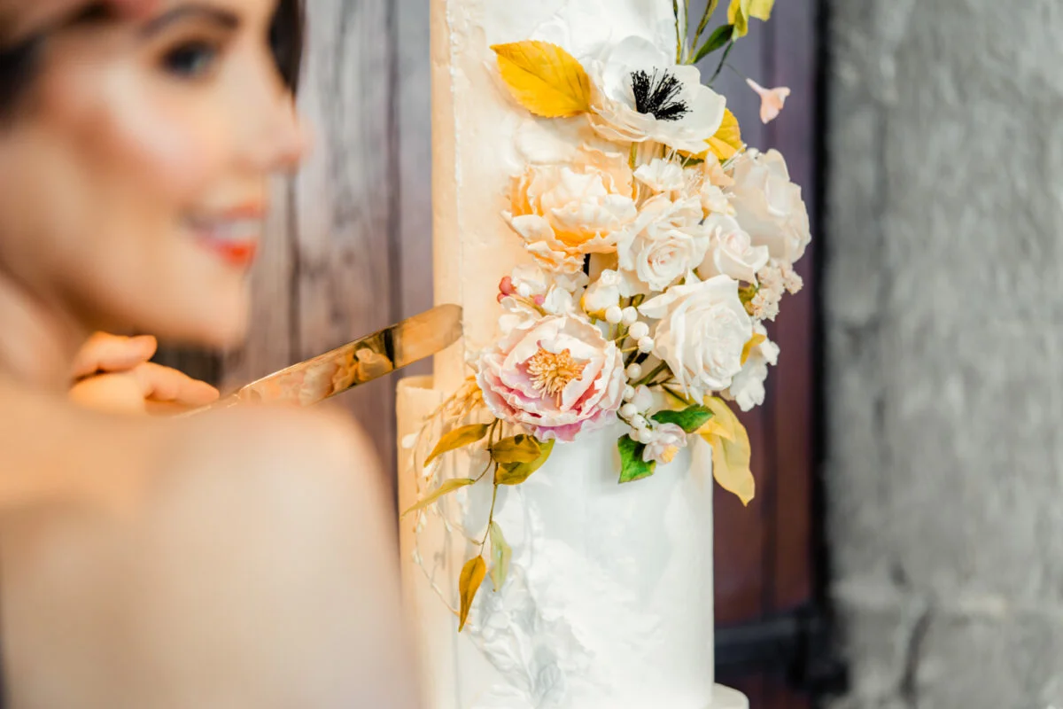 A woman is cutting a cake with flowers on it.