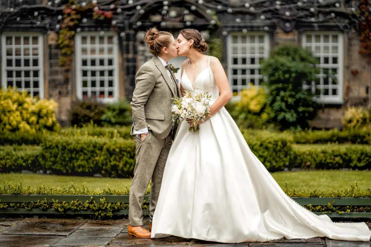 A bride and groom kissing in front of a building.