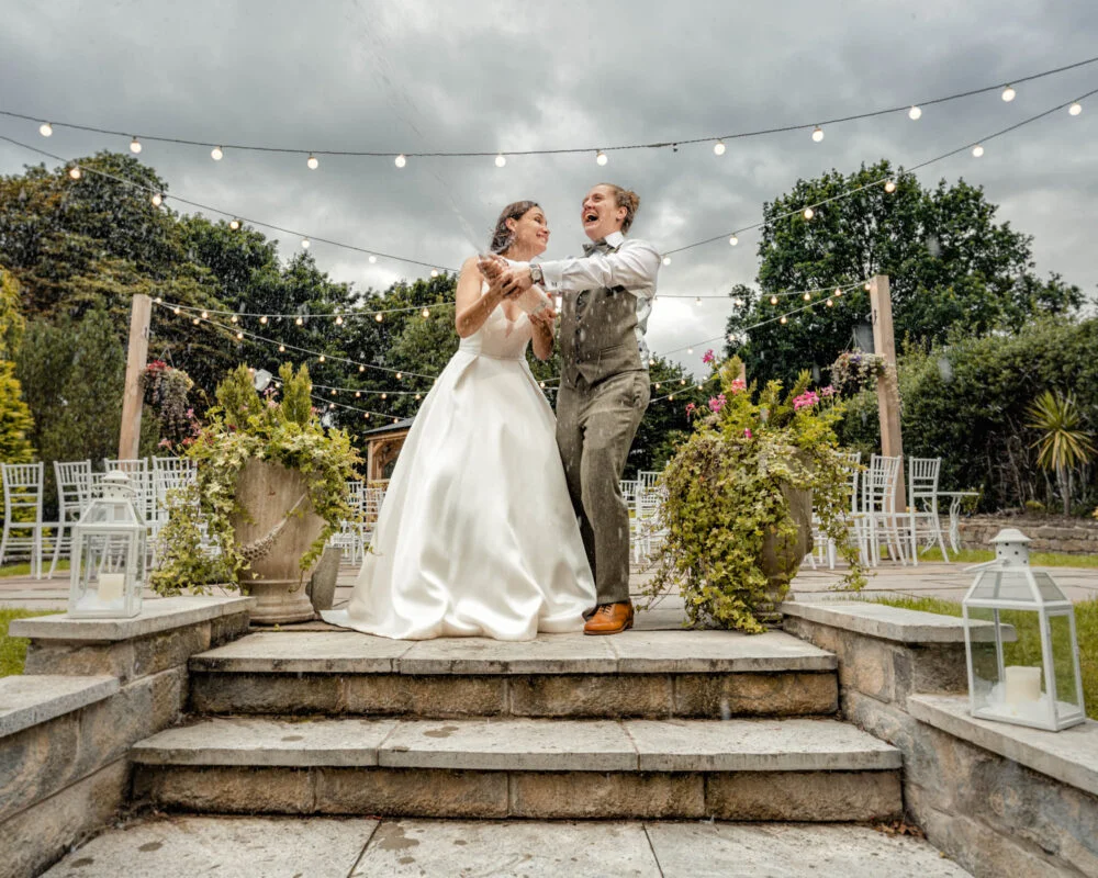 A bride and groom standing on steps in a garden.