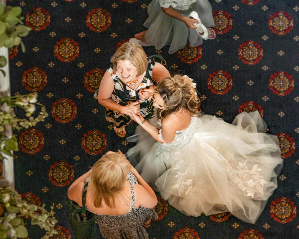 A bride and her bridesmaids looking at each other from the top of the room.