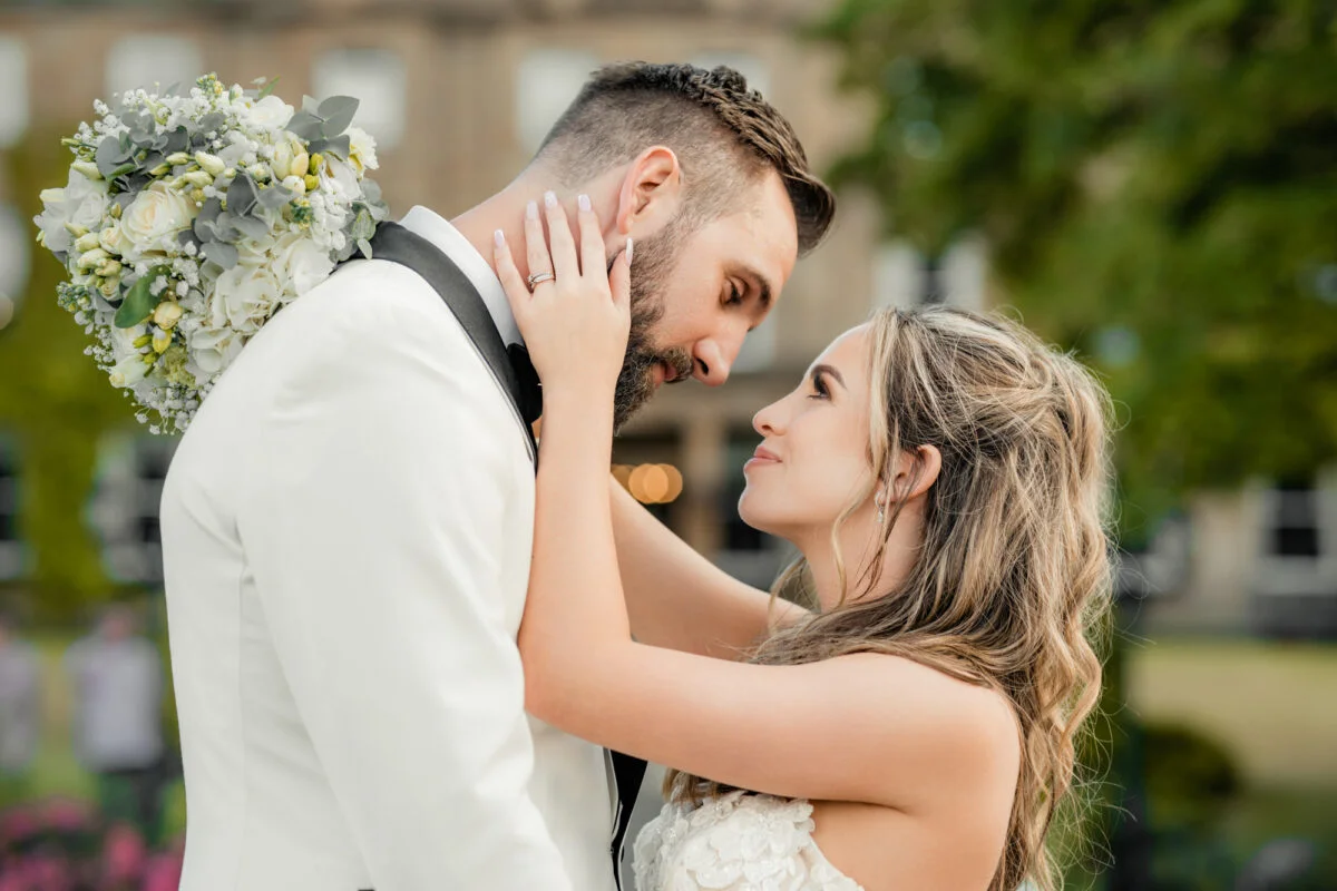 A bride and groom embracing in front of a large building.