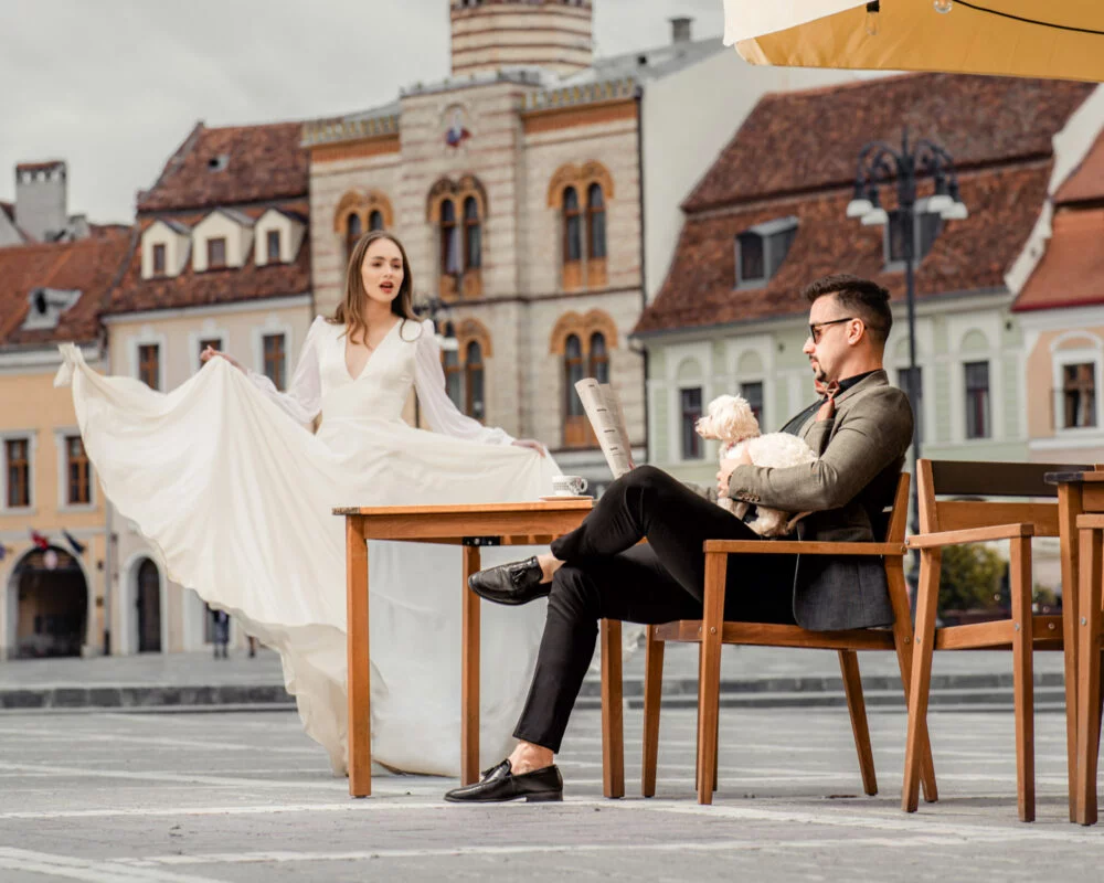A bride and groom sitting on a bench with a teddy bear.
