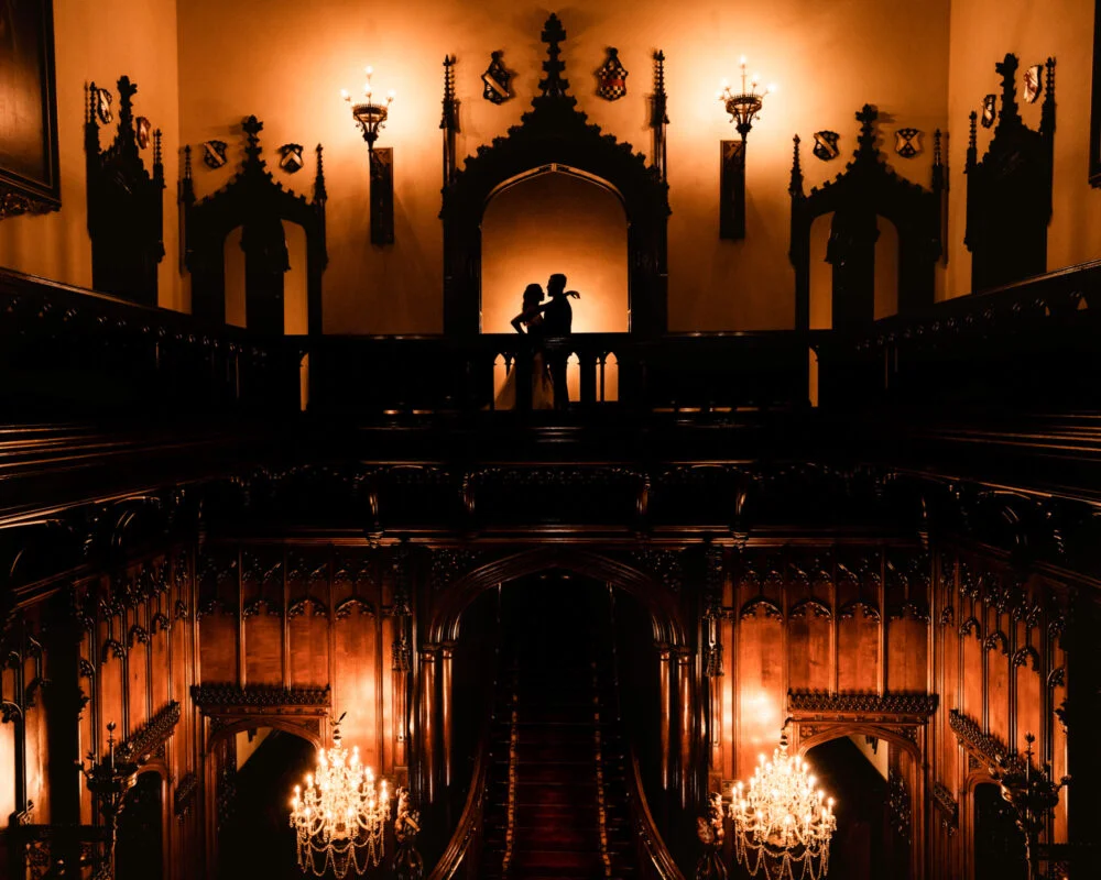 A bride and groom standing on a staircase in an ornate building.