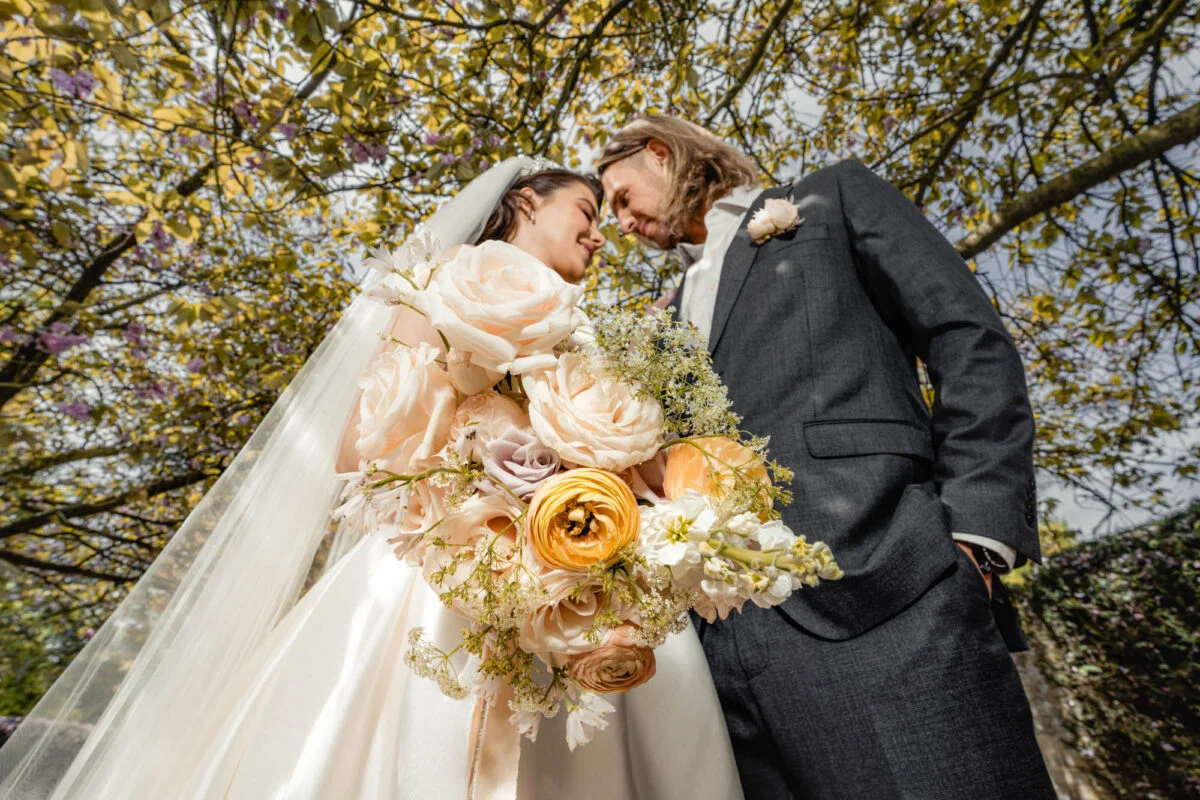 A bride and groom embracing under a tree.