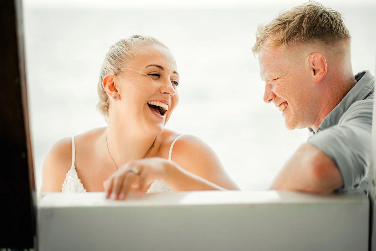 A man and woman laughing on a boat.