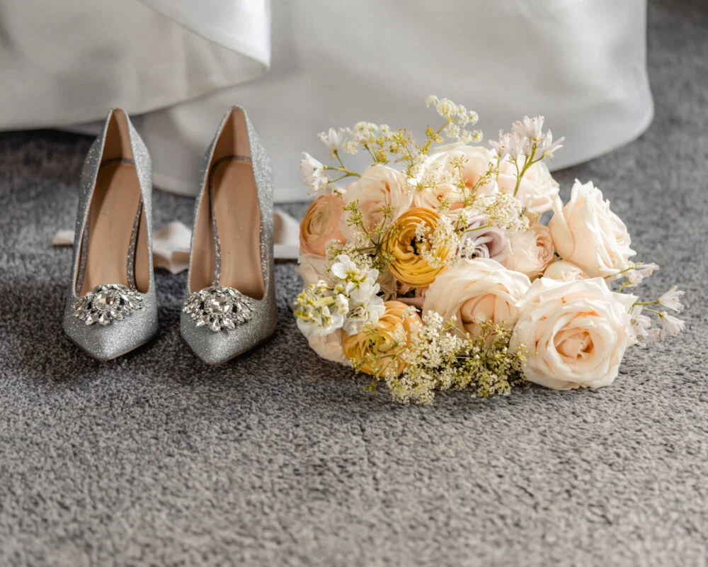 A bouquet of flowers and a pair of wedding shoes.