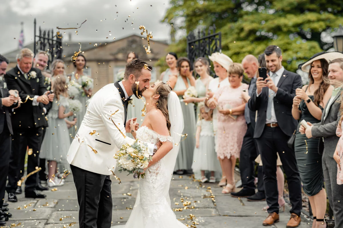 A bride and groom kissing in front of confetti.