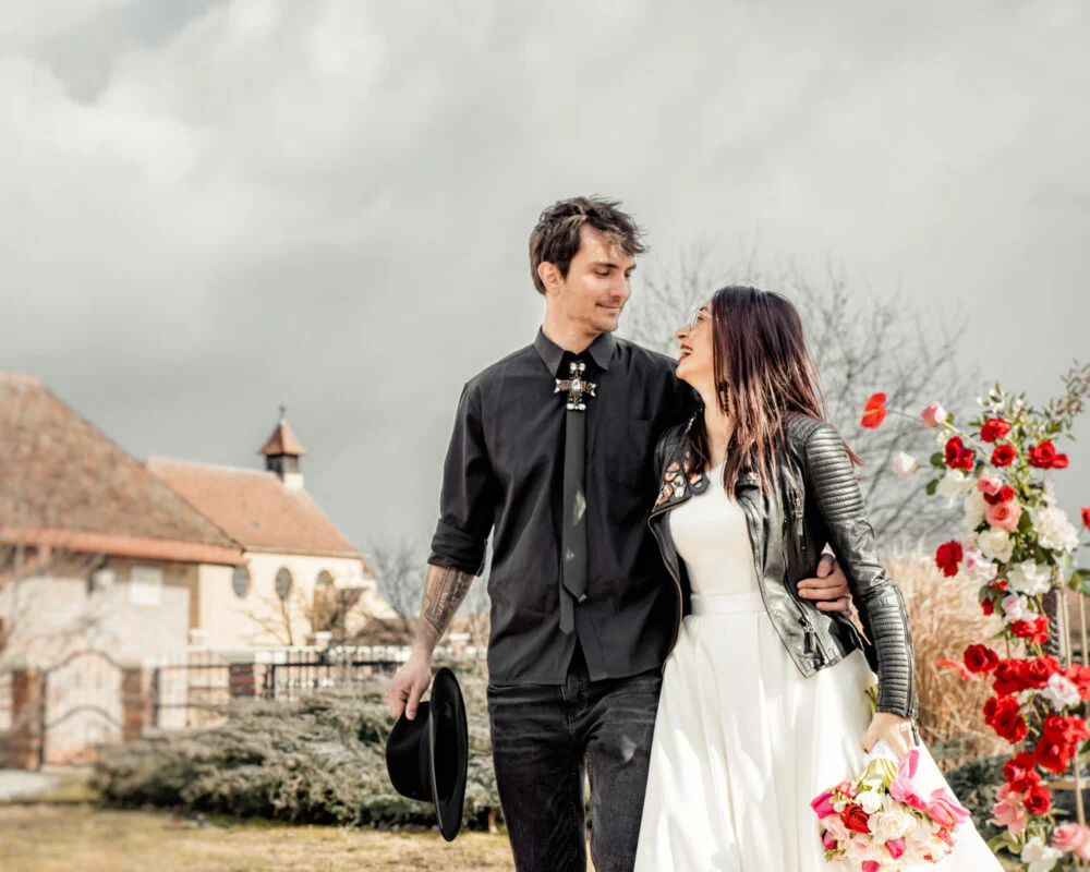 A bride and groom standing in front of a barn.