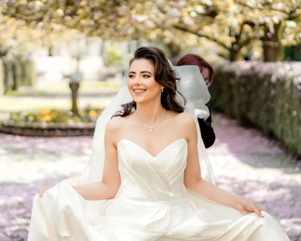 A bride in a wedding dress sitting in a garden.