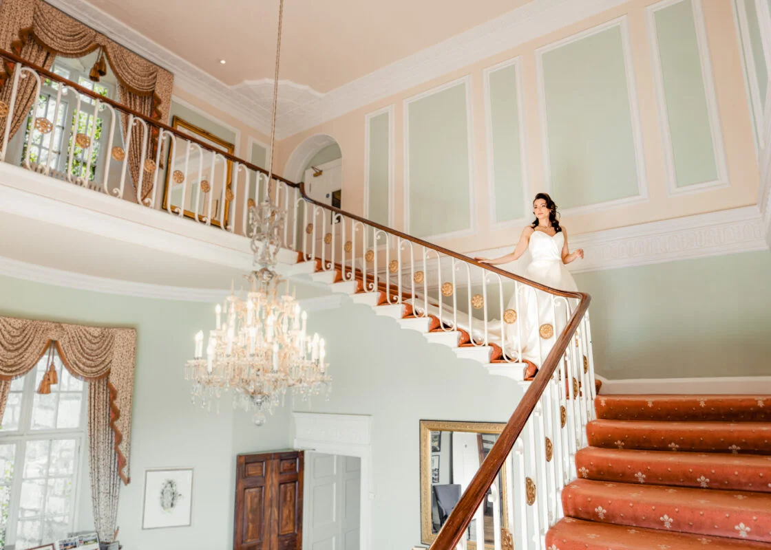 A bride standing on the stairs of a large house.