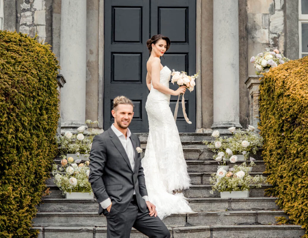 A bride and groom standing on the steps of a house.