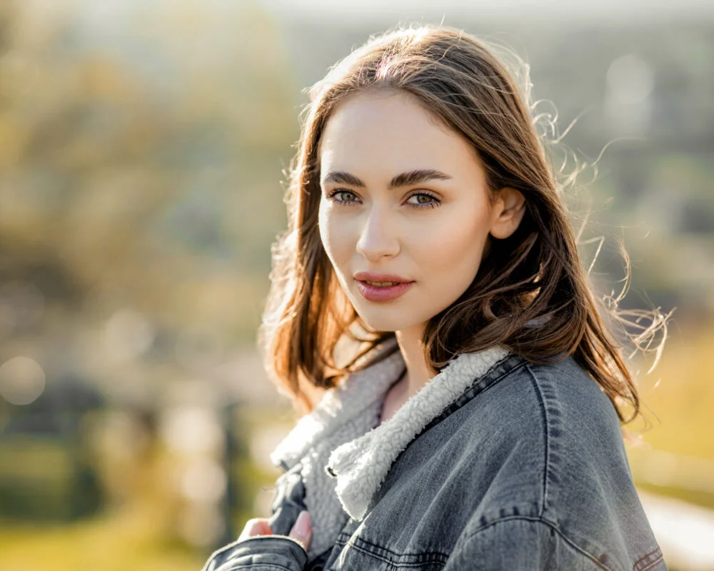 A young woman in a denim jacket is posing for a photo.