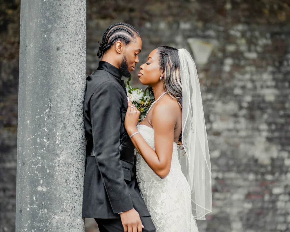 A bride and groom leaning against a column.