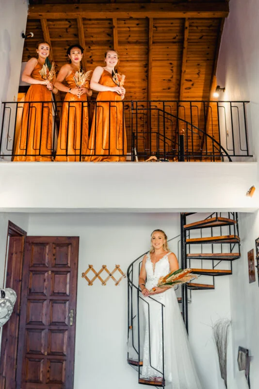 A bride and her bridesmaids standing on a staircase.
