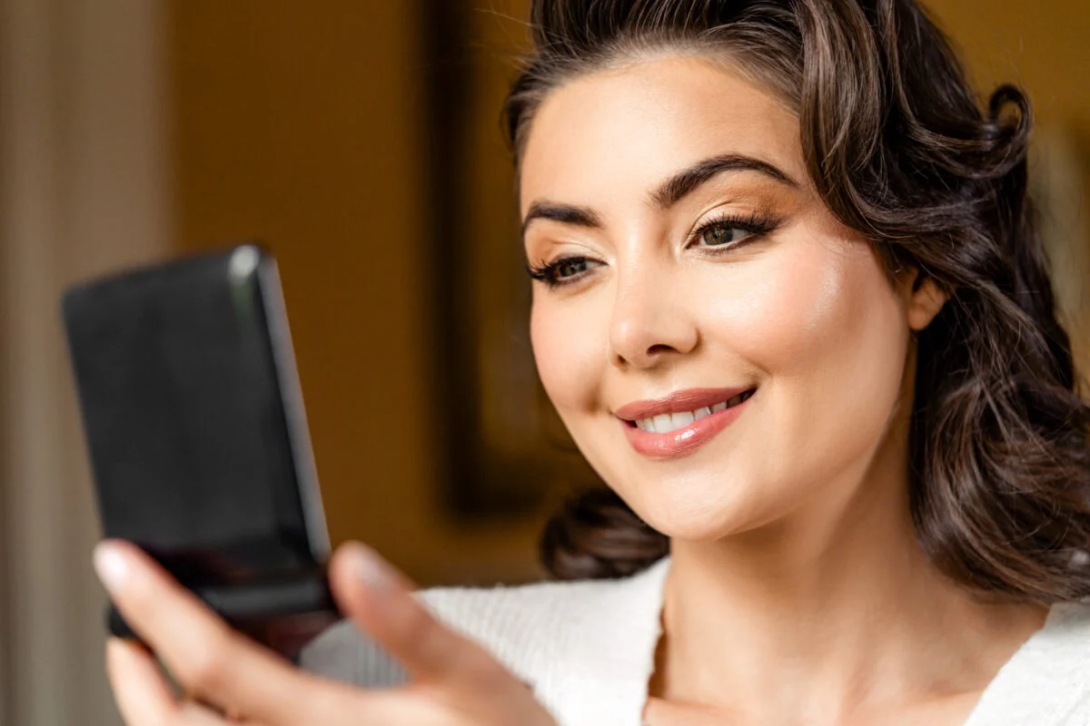 A woman is looking at her phone and smiling.
