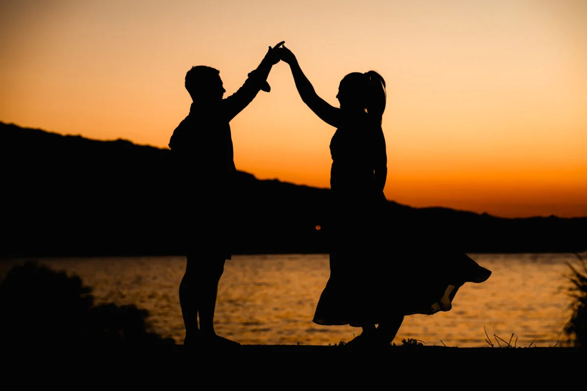 A silhouette of a couple holding hands at sunset.