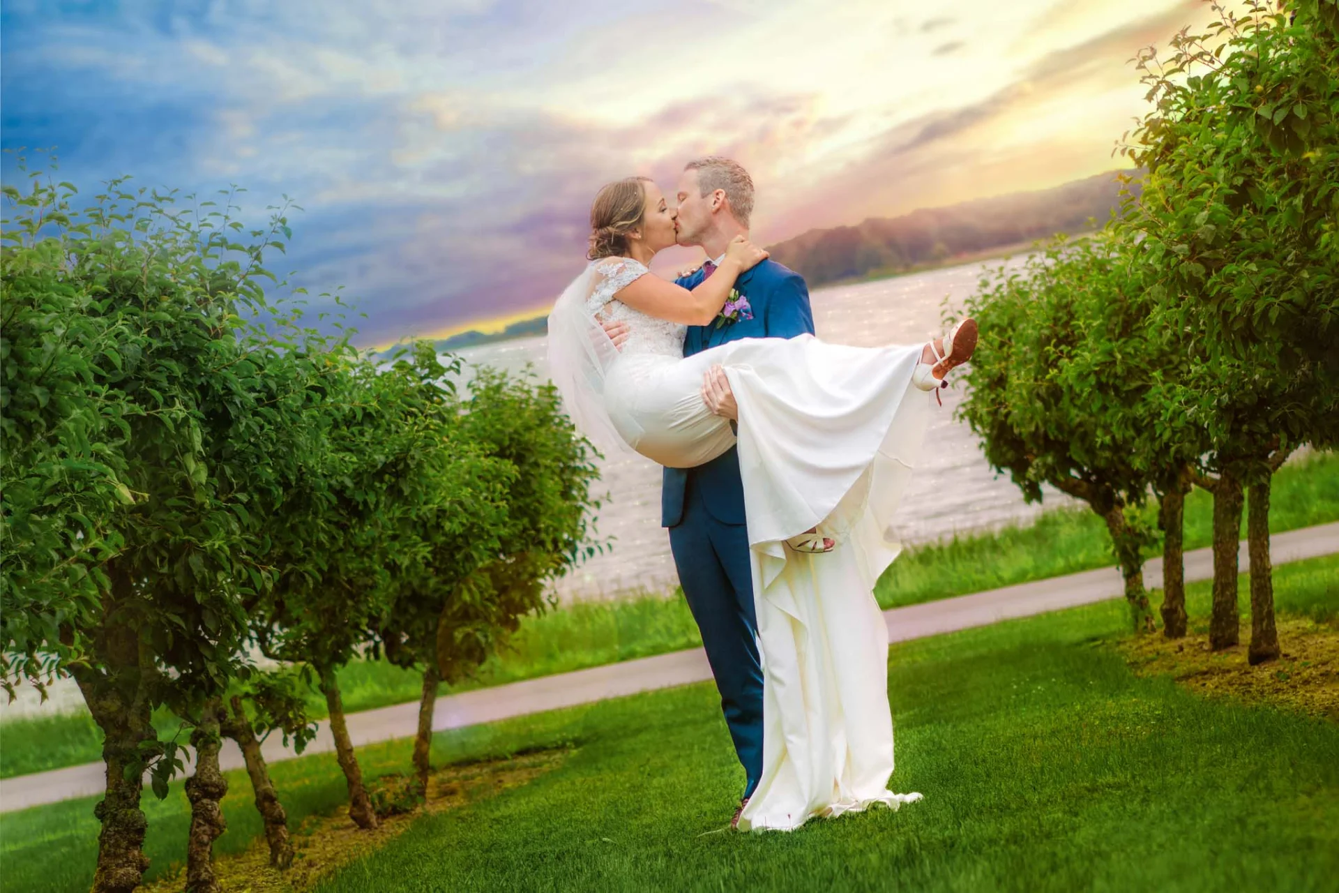 A fairytale wedding couple kissing in front of a vineyard at sunset. (listing)