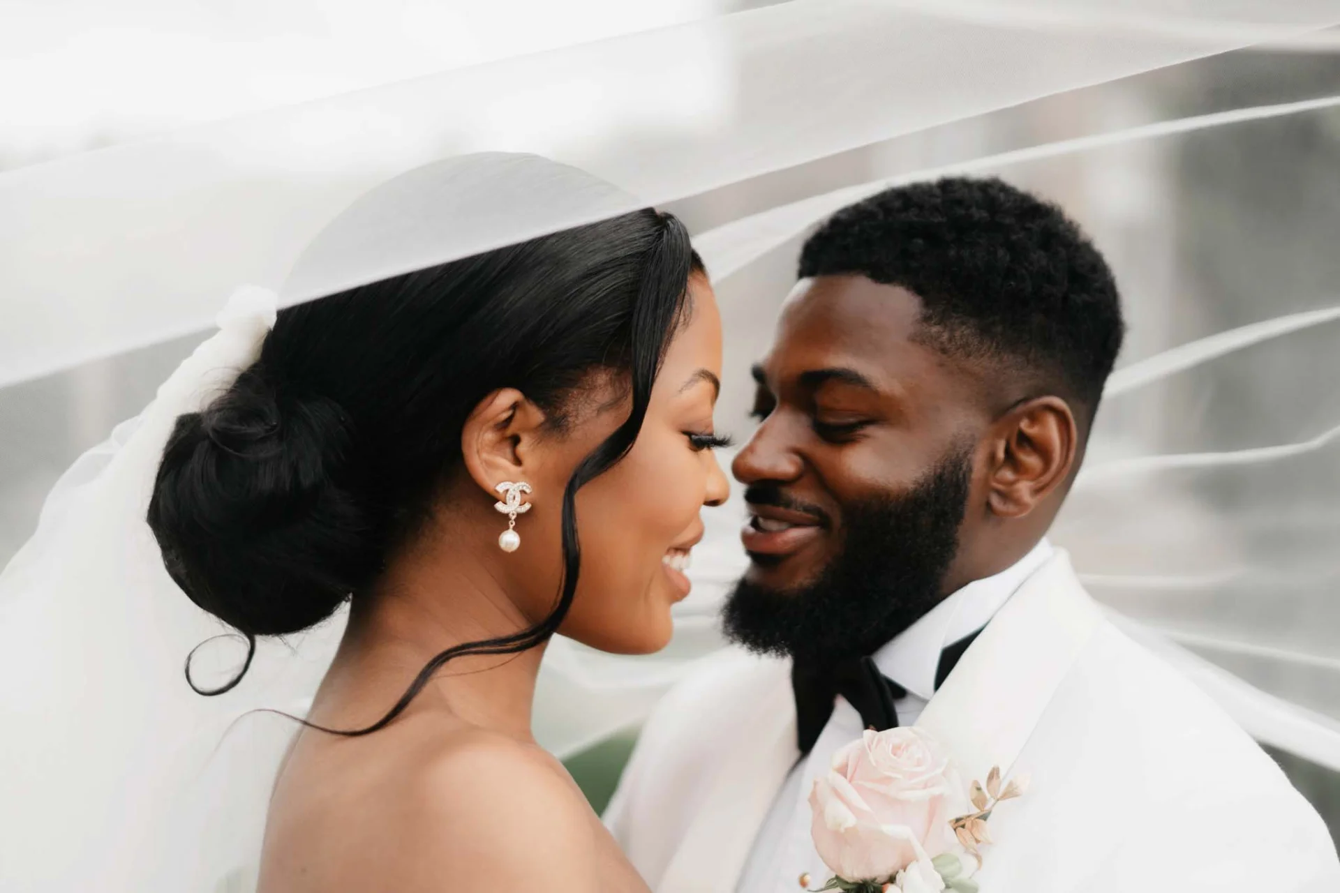 A fairytale bride and groom sharing a kiss under a veil in romantic wedding photography. (listing)