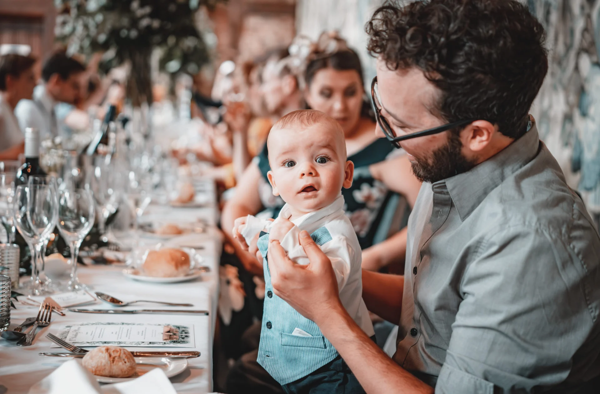 A baby is sitting at a table at a fairytale wedding reception, captured in enchanting wedding photography. (listing)