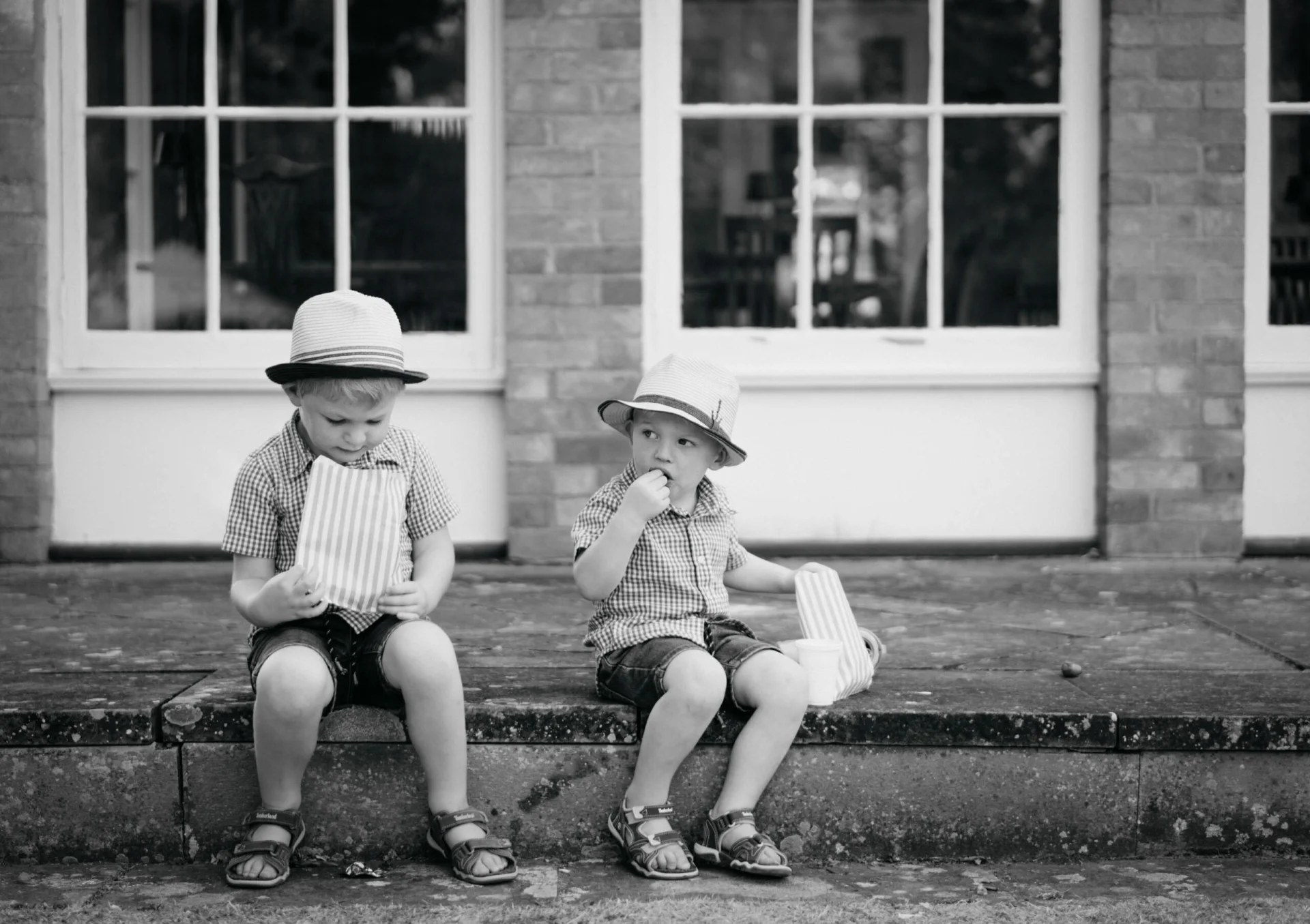 Two boys in hats sitting on the steps of a fairytale building. (listing)