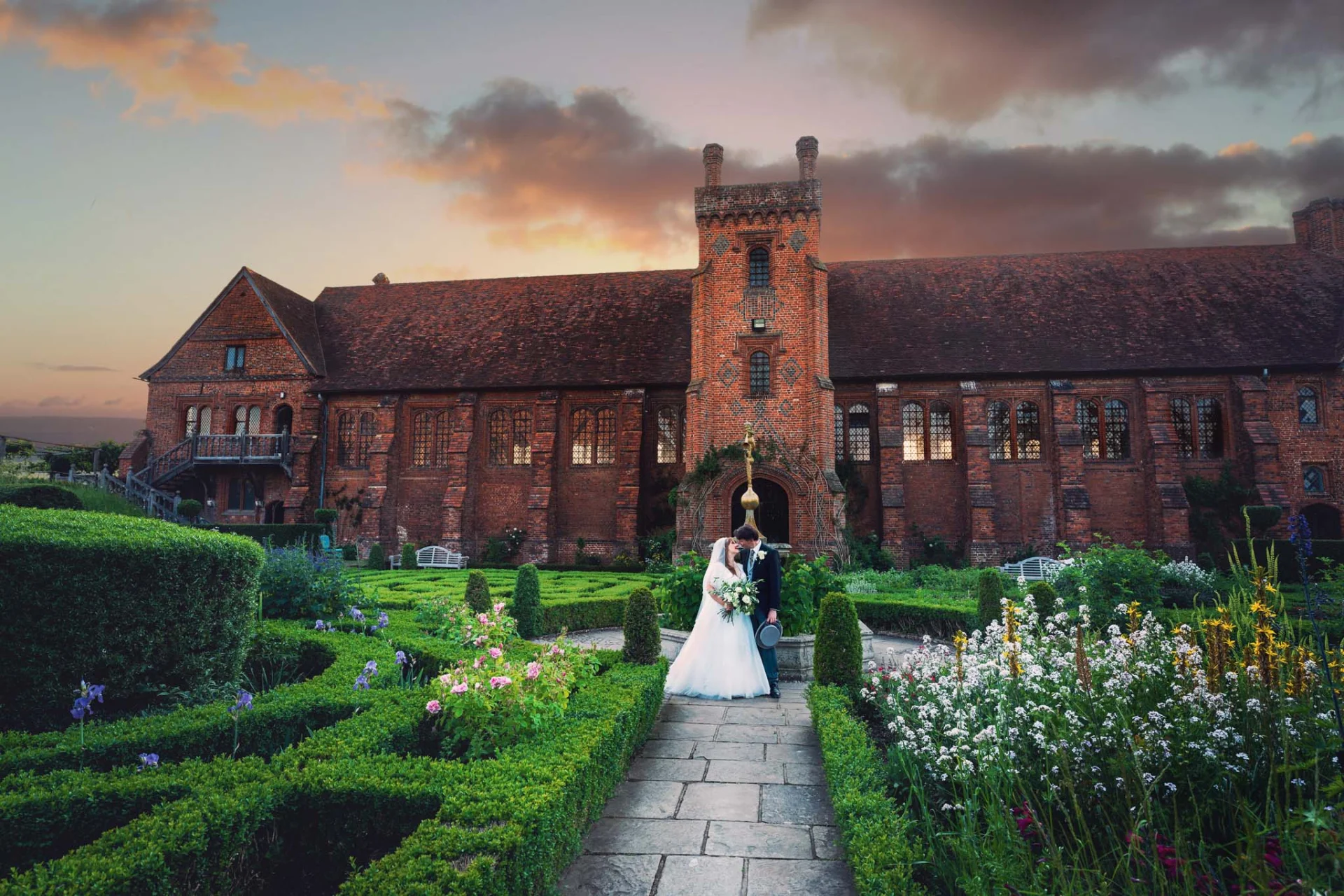 Fairytale wedding couple in front of a brick building at sunset. (listing)
