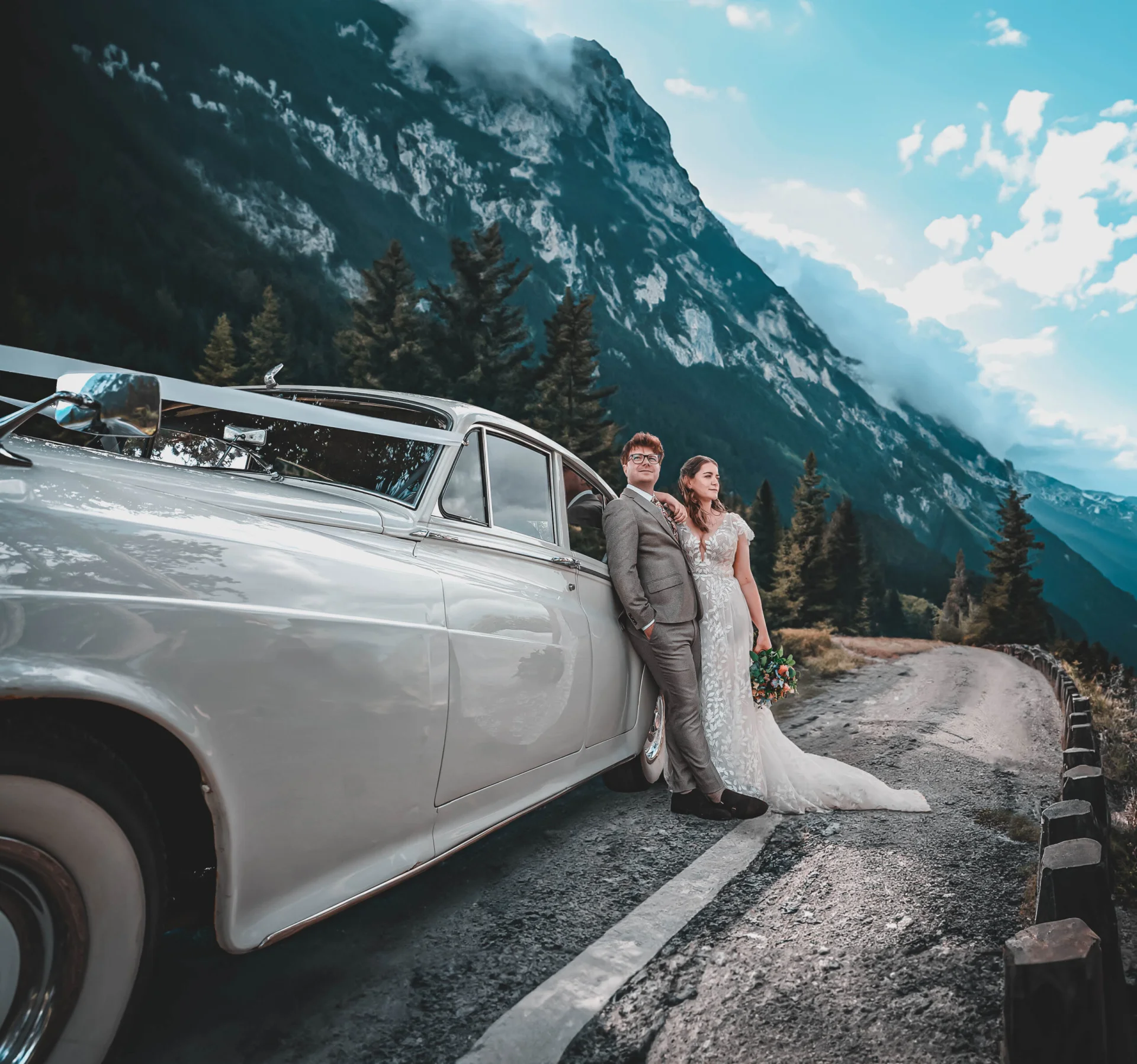 Fairytale bride and groom posing next to a vintage car in the mountains. (listing)