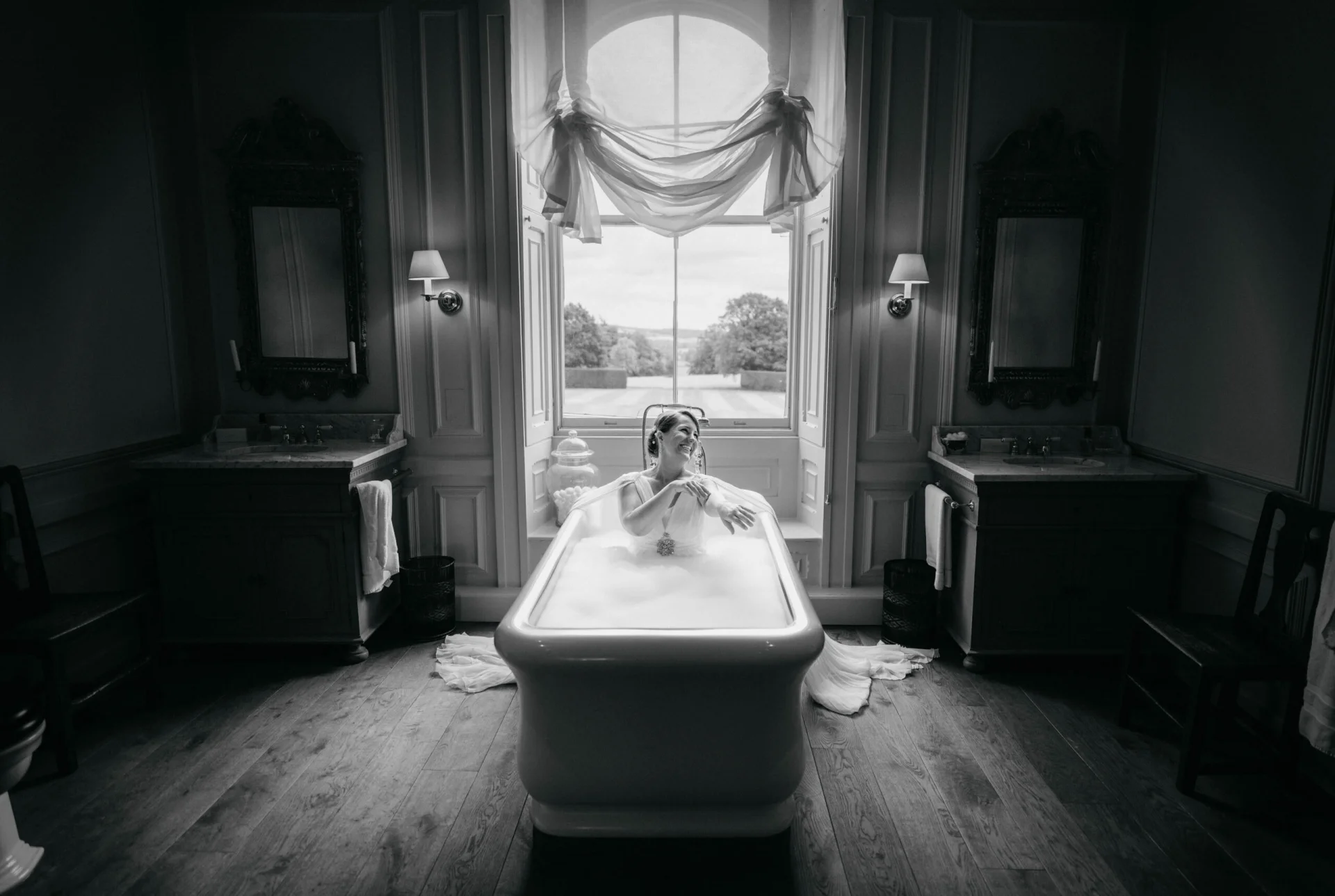 A bride is sitting in a fairytale bathtub in front of a window. (listing)