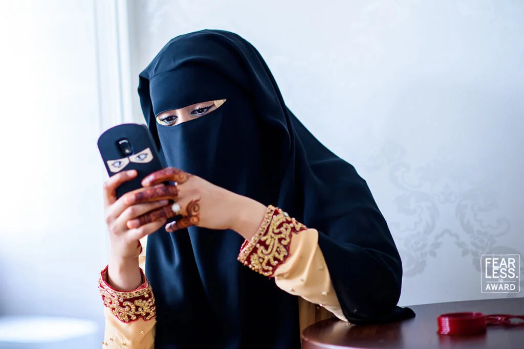 A woman in a burka looking at her cell phone.