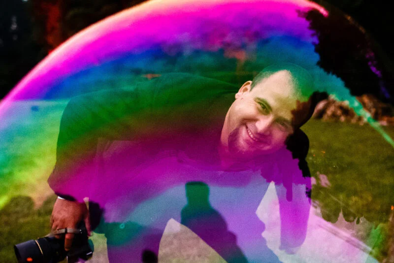A man standing in front of a colorful soap bubble.