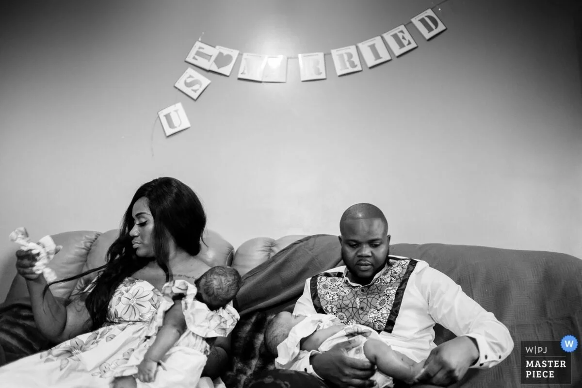 A black and white photo of a family sitting on a couch.