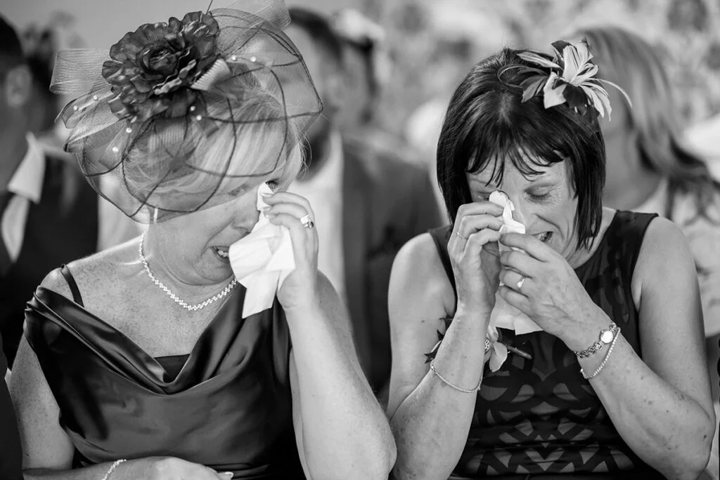 Black and white photo of two women crying at a wedding.
