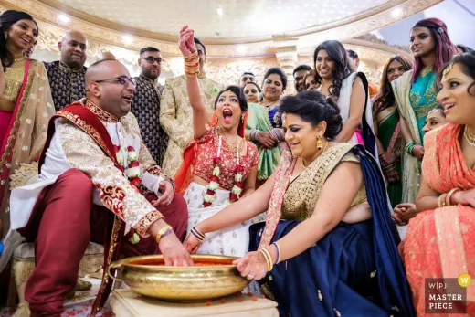 An indian wedding ceremony with a bride and groom pouring water into a bowl.