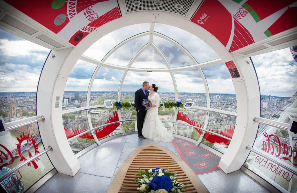 A bride and groom are standing inside the london eye.