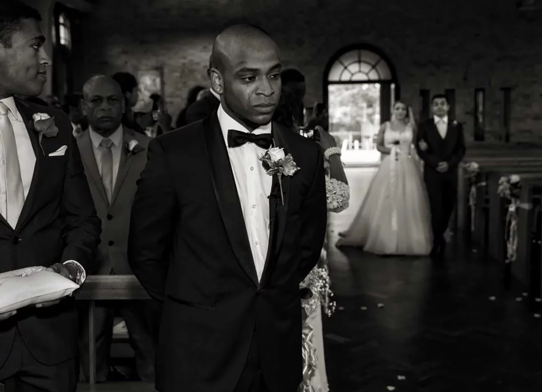 A man in a tuxedo walks down the aisle.