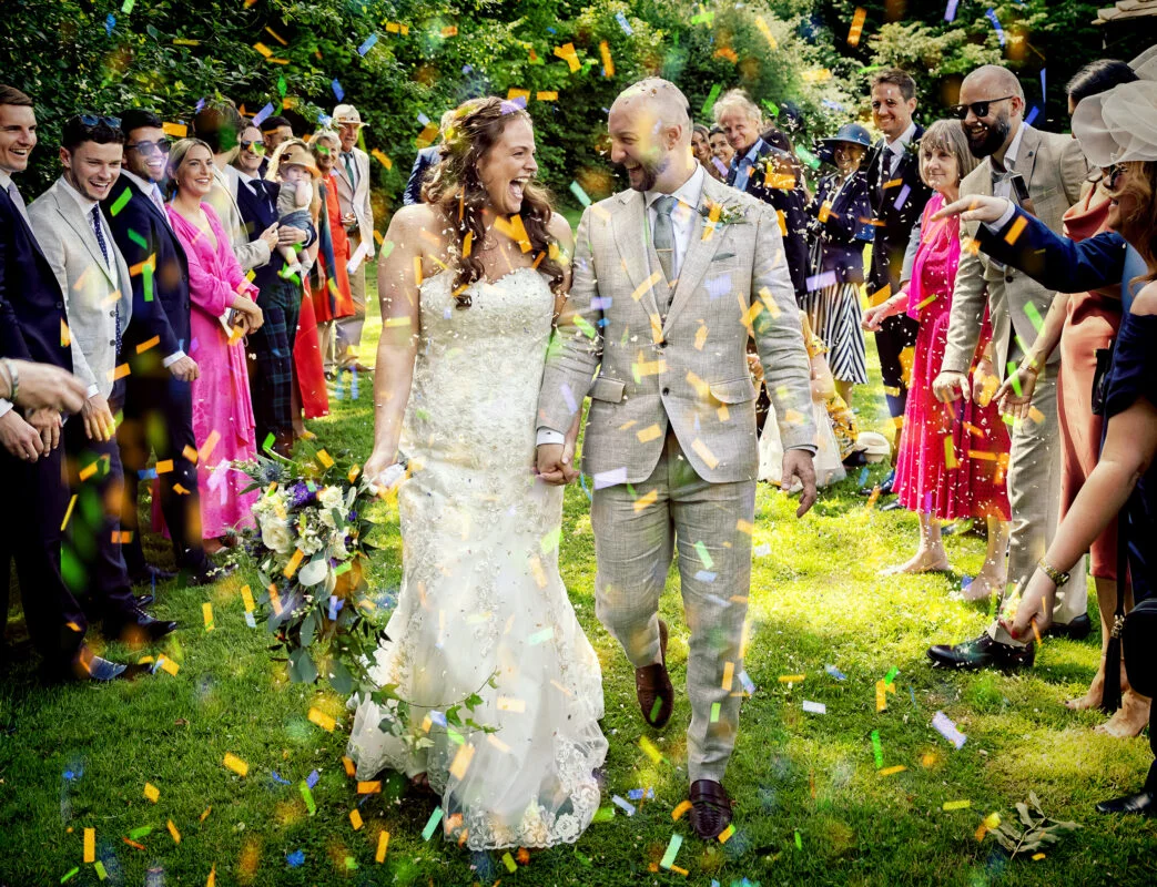A bride and groom walk through confetti at their wedding.