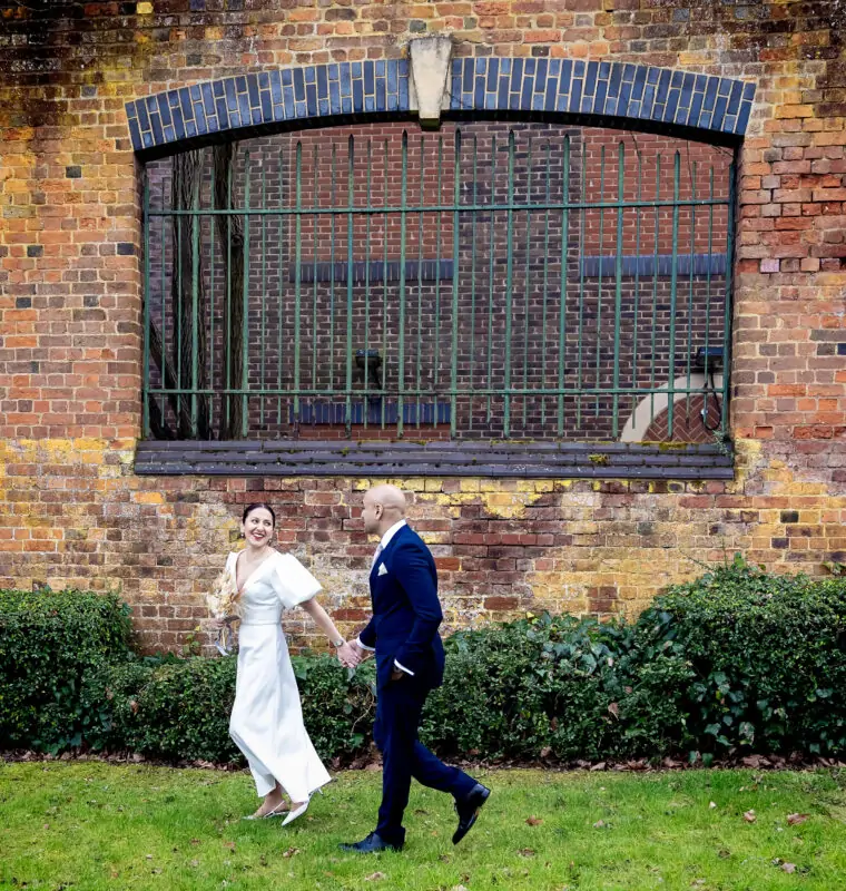 St-Albans-registry-wedding-couple-run-past-wall-image