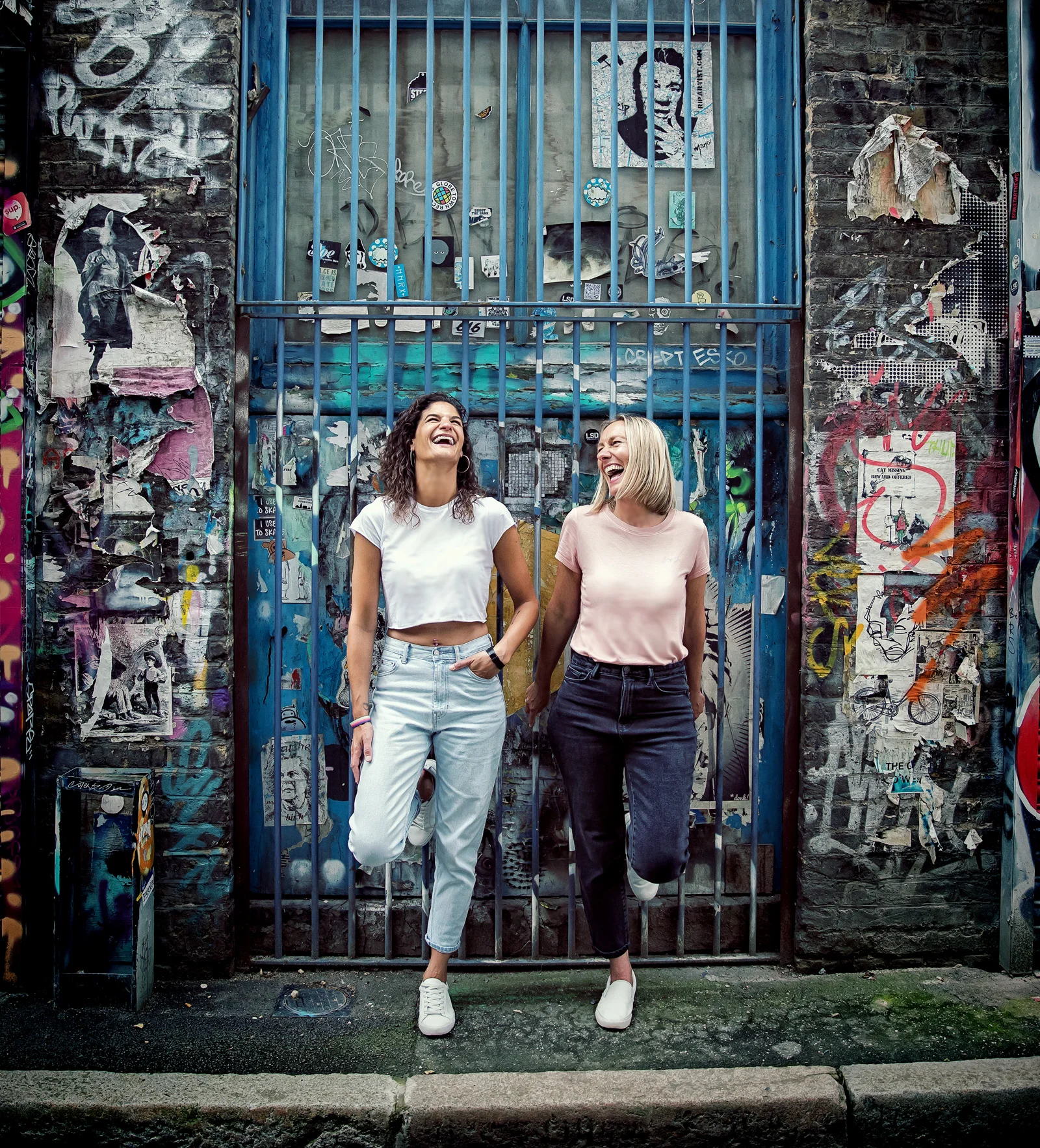 Shoreditch-engagment-shoot-girls-laugh-by-iron-doors-cropped (listing)