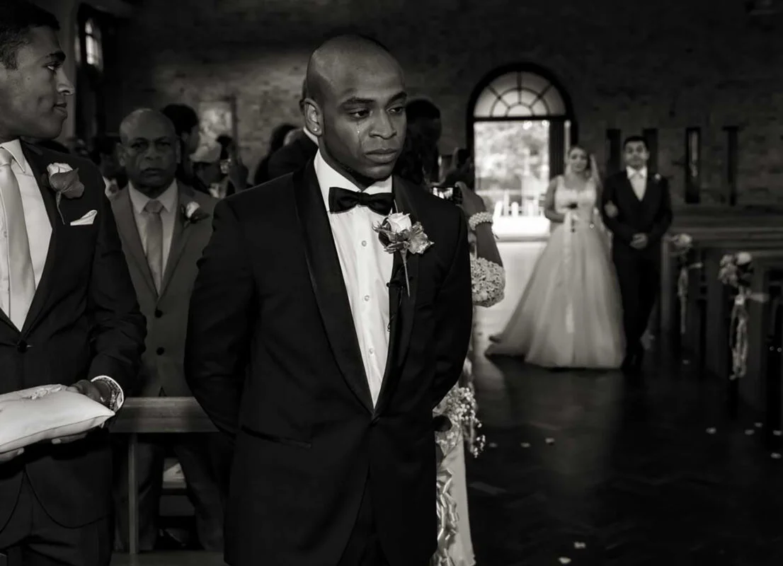 A man in a tuxedo walks down the aisle.