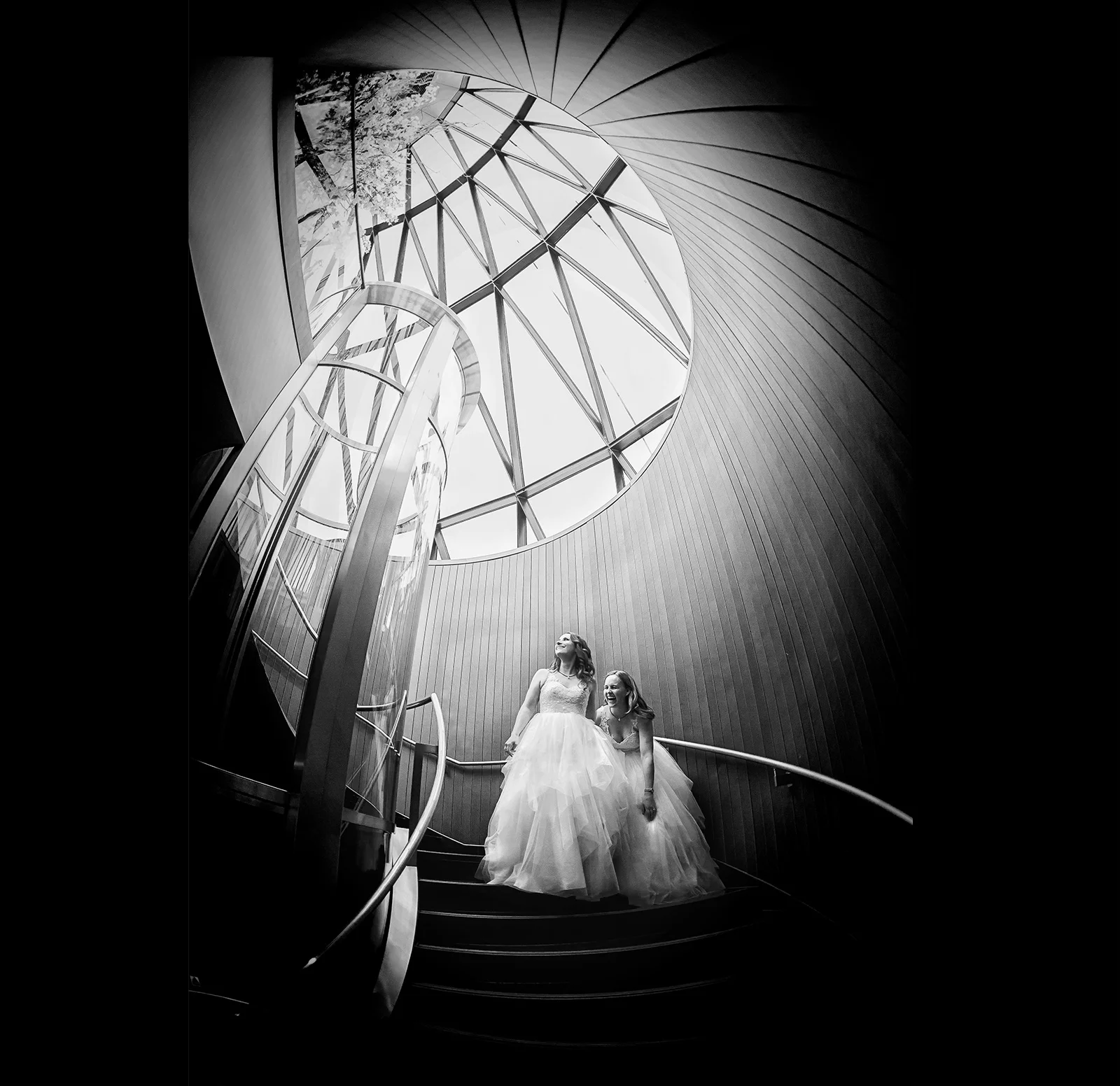 Two brides captured by a wedding photographer duo grace a stunning spiral staircase. (listing)