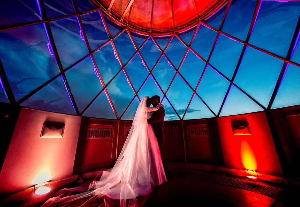 A bride and groom standing inside a dome.