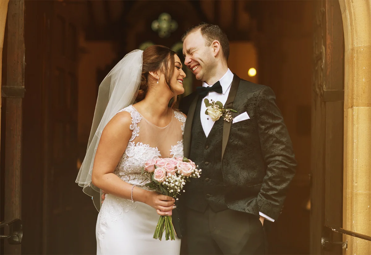 Bride-and-groom-laugh-in-church-doorways-at-London-wedding (listing)