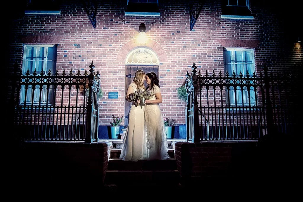 Wedding photographer duo capturing two brides at night. (listing)