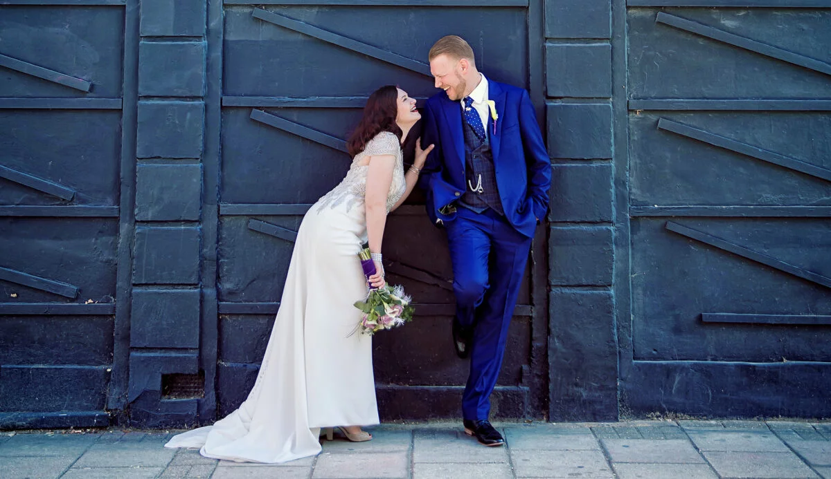 A bride and groom kissing in front of a black door.
