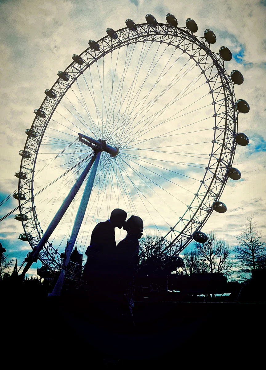 A wedding photographer couple capturing a kiss in front of the London Eye. (listing)