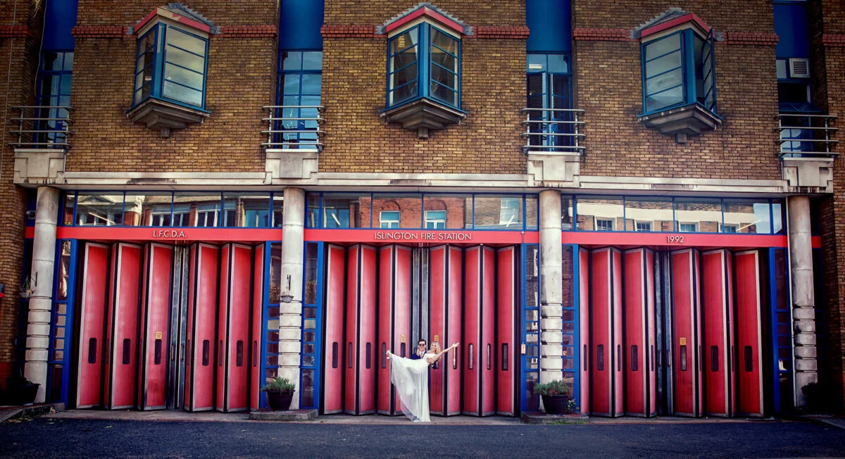 A woman is standing in front of a building with red doors.